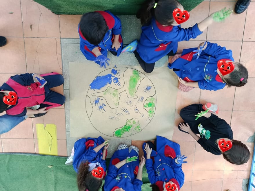 Niños y niñas pintando un gran dibujo del planeta Tierra
