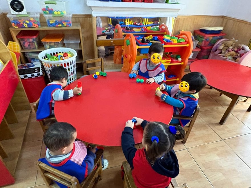 Niños y niñas compartiendo materiales en una mesa de bienvenida