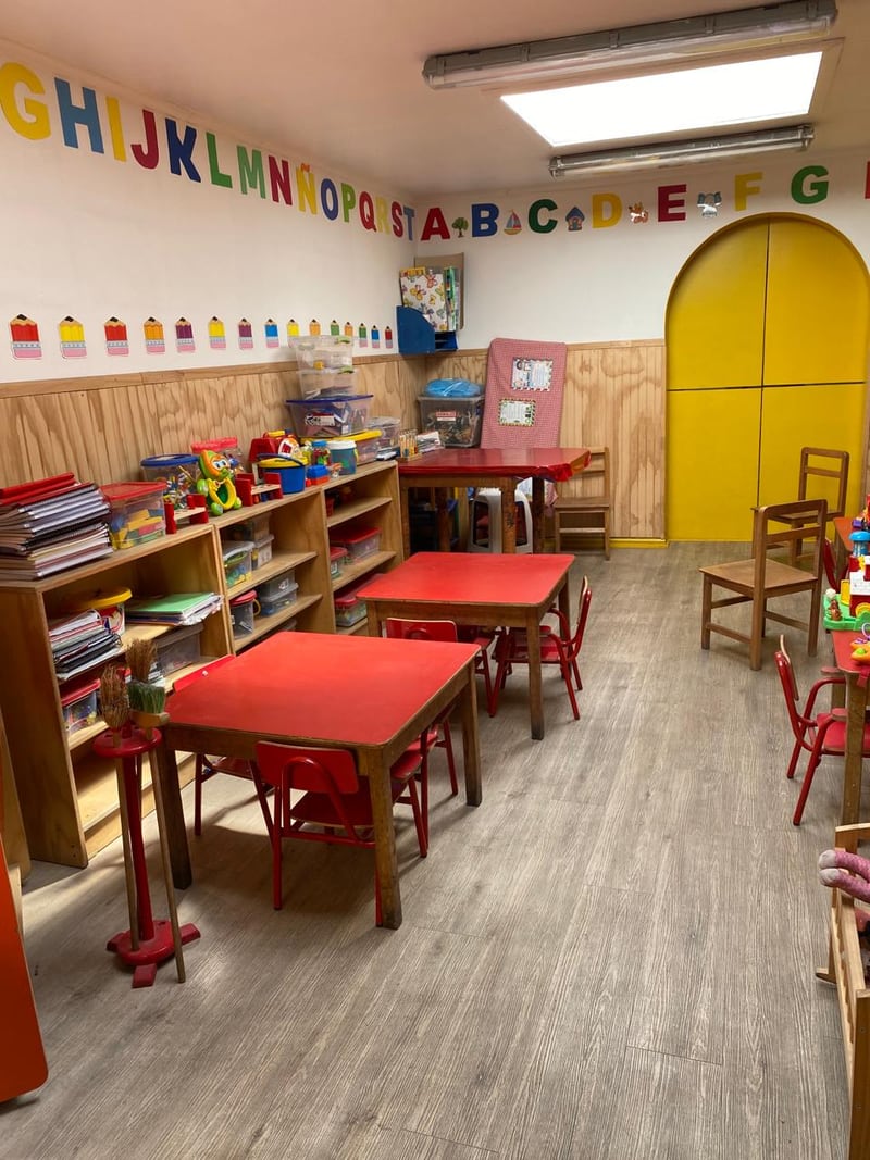 Sala de actividades con mesas, sillas y materiales al alcance