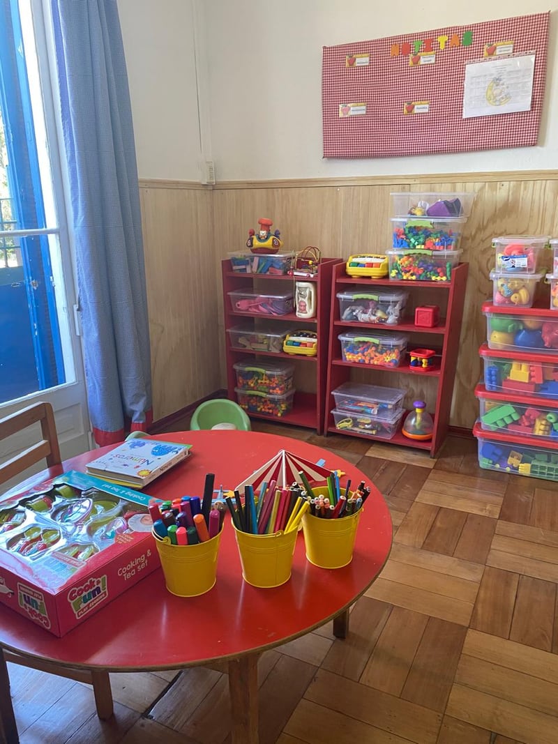 Sala equipada con mesas, sillas y rincones de aprendizaje
