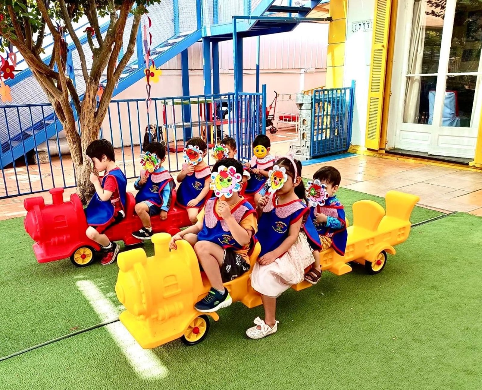 Niños y niñas de Semillita sentados en trenes de juguete en el patio